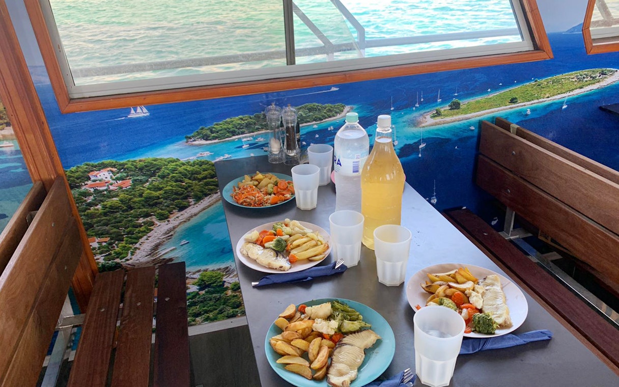 Lunch setup on a cruise with plates of fish and vegetables, Split Blue Lagoon tour.
