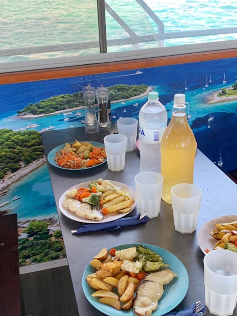 Lunch setup on a cruise with plates of fish and vegetables, Split Blue Lagoon tour.