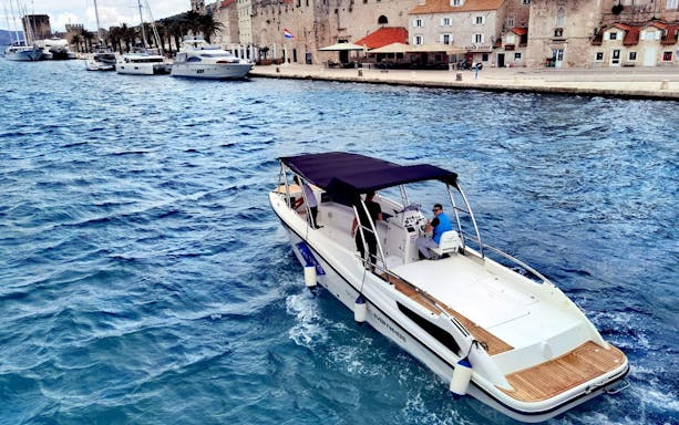 Boat cruising along Split Riviera with historic buildings and yachts in the background.
