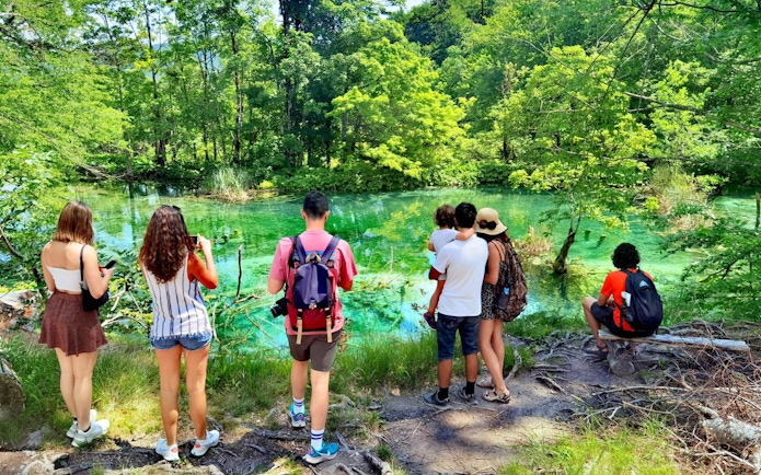 Tourists enjoying the view of a turquoise lake at Plitvice Lakes National Park.