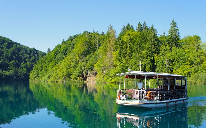 Boat ride on a lake surrounded by lush forest at Plitvice Lakes National Park.