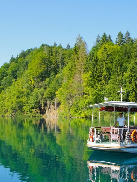 Boat ride on a lake surrounded by lush forest at Plitvice Lakes National Park.