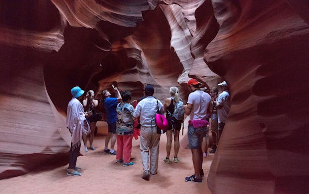 Tour group exploring the narrow sandstone walls of Antelope Canyon.