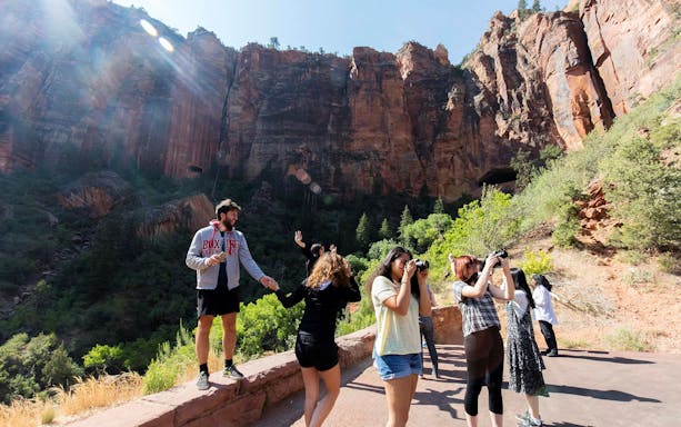 Tourists photographing red rock formations at Zion Park.