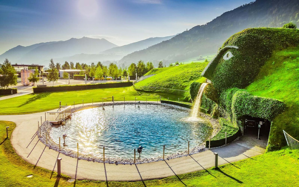 Swarovski Crystal Worlds entrance with giant grass-covered head and waterfall in Innsbruck, Austria.