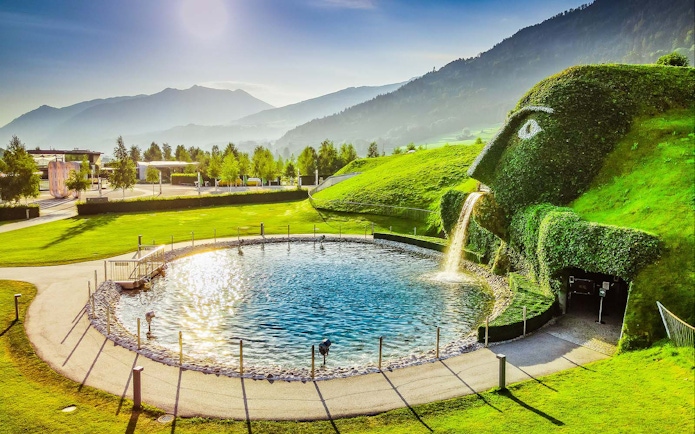 Swarovski Crystal Worlds entrance with giant grass-covered head and waterfall in Innsbruck, Austria.