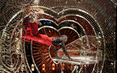 Performer in Swarovski Crystal Worlds display with crystal piano and heart backdrop.