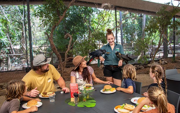 Family dining with birds at a wildlife habitat.