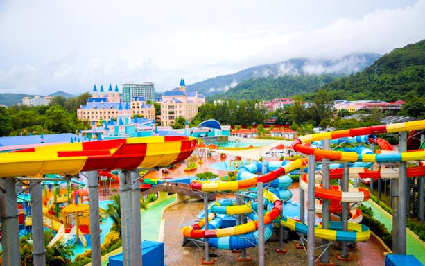 Colorful water slides at Splash Out water park, Langkawi, with scenic mountain backdrop.