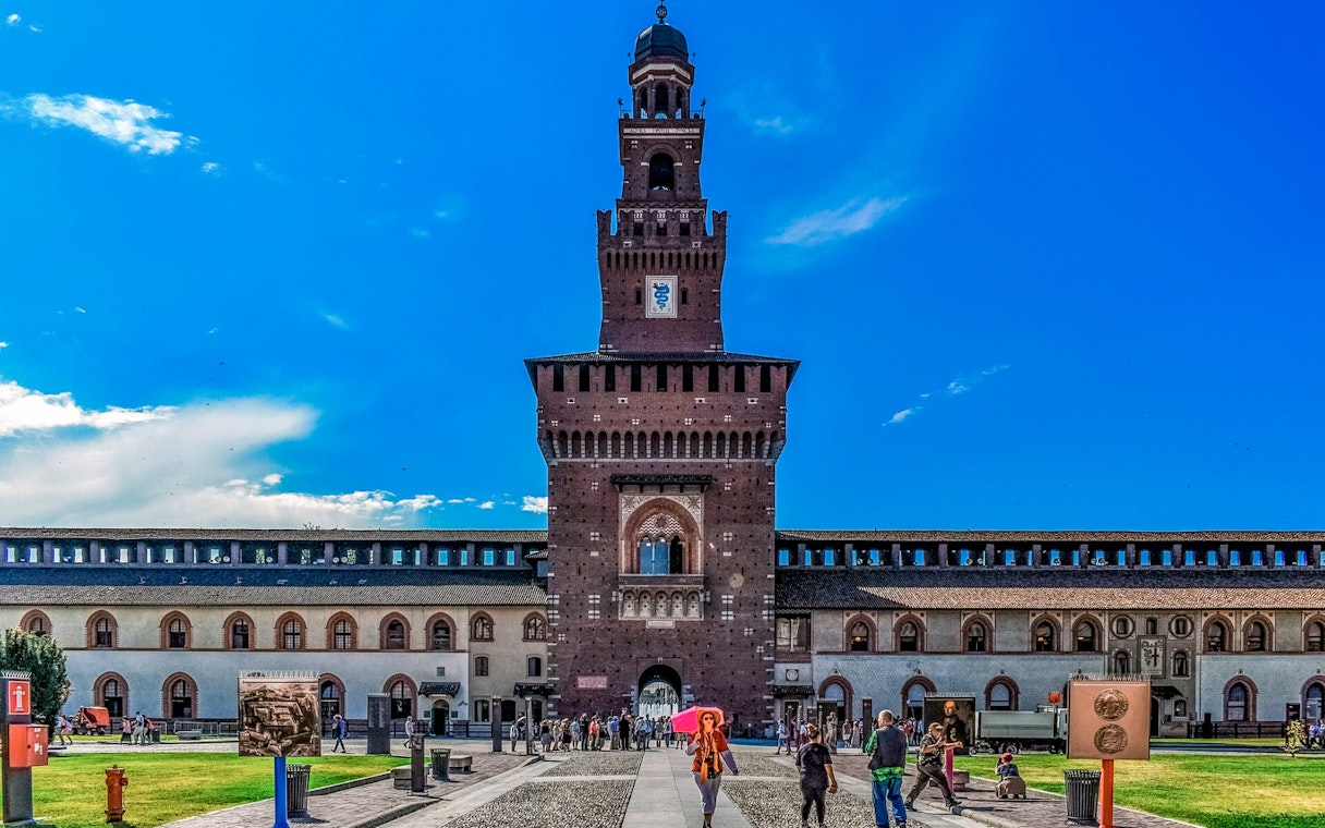 Sforza Castle entrance with visitors in Milan, Italy.