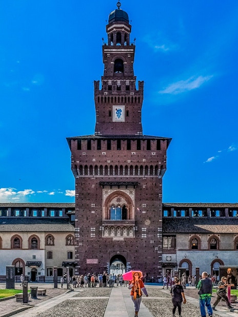 Sforza Castle entrance with visitors in Milan, Italy.