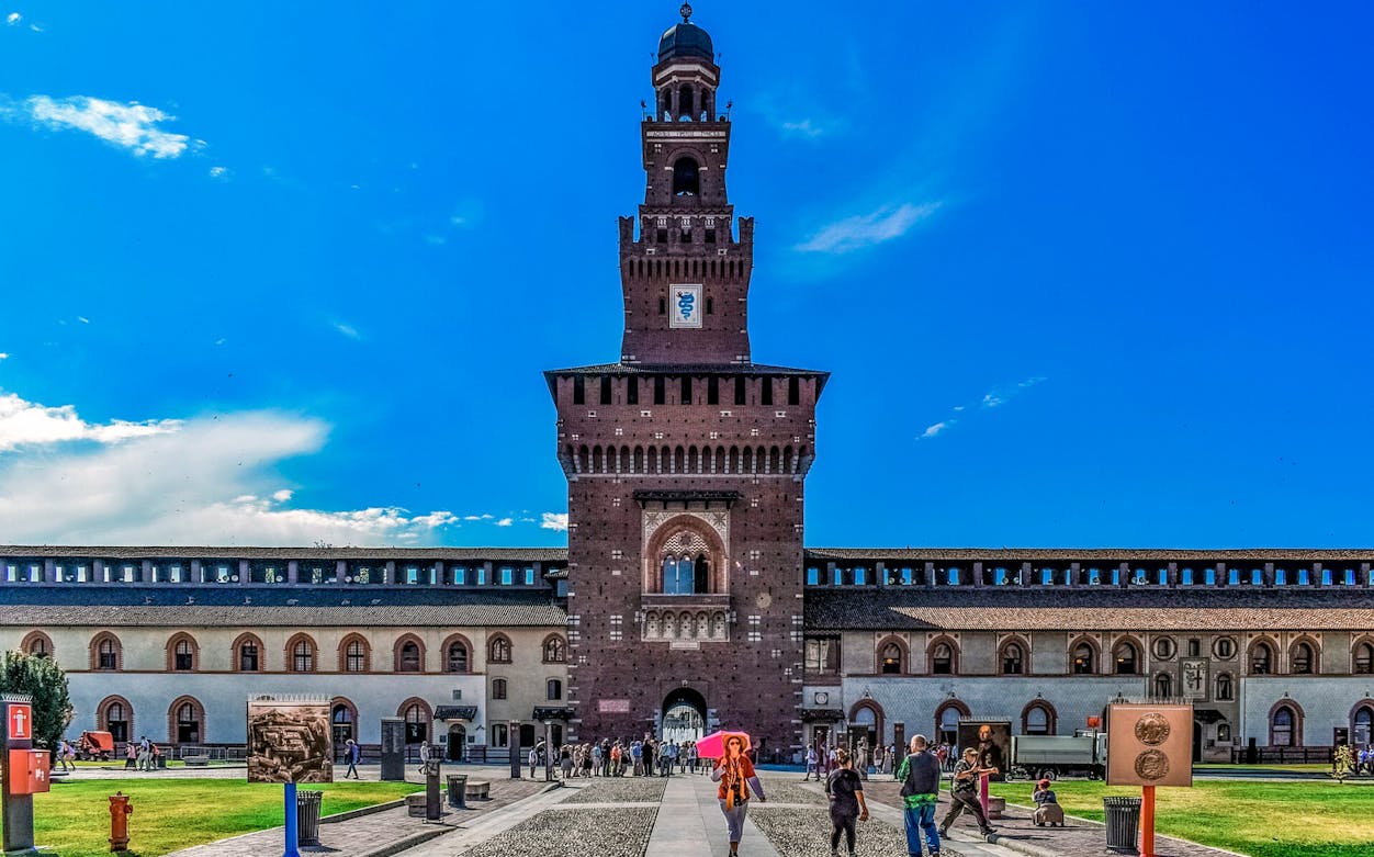 Sforza Castle entrance with visitors in Milan, Italy.