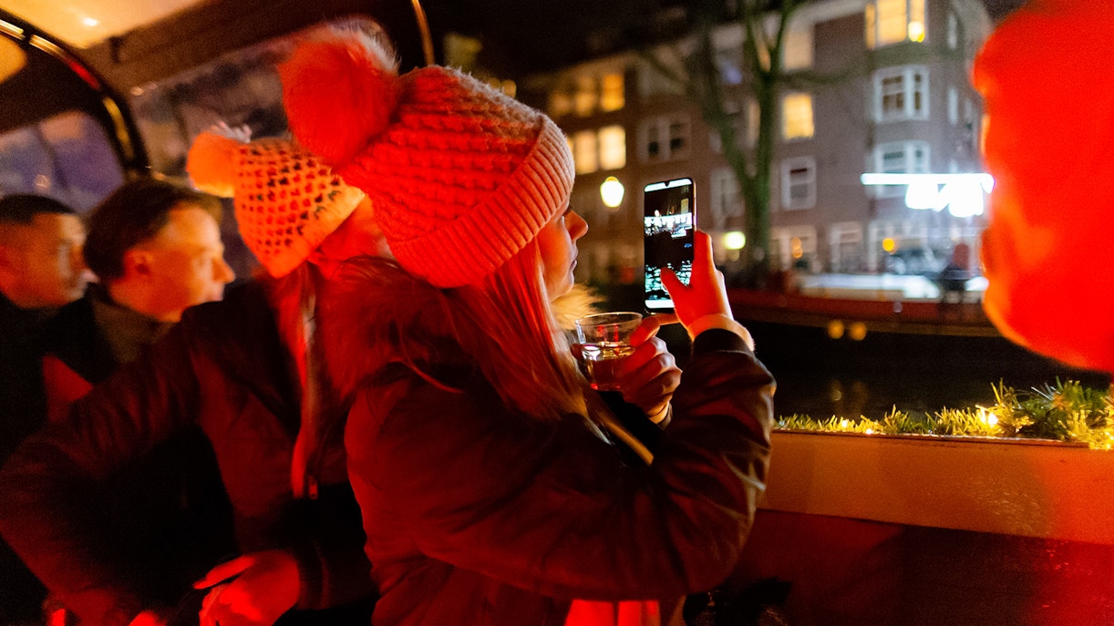Guests enjoying an Amsterdam evening canal cruise, capturing city lights.