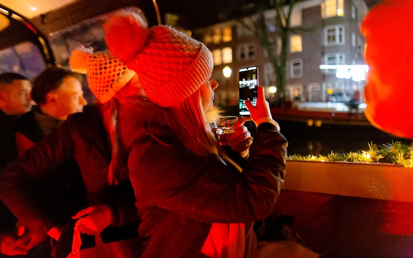 Guests enjoying an Amsterdam evening canal cruise, capturing city lights.