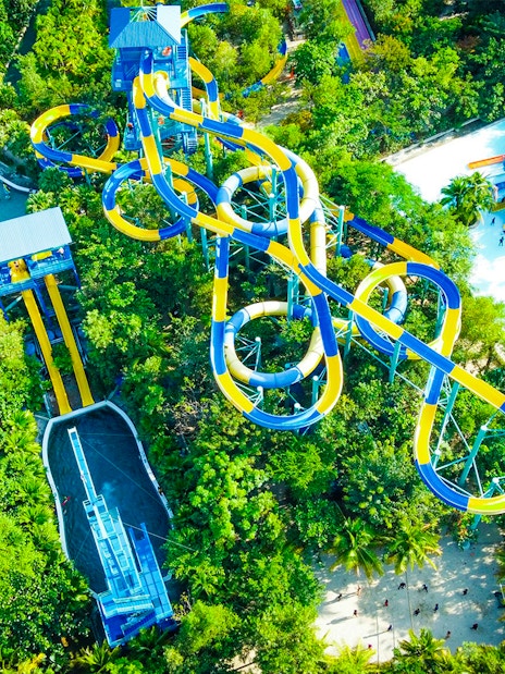 Aerial view of colorful water slides at ESCAPE Penang surrounded by lush greenery.