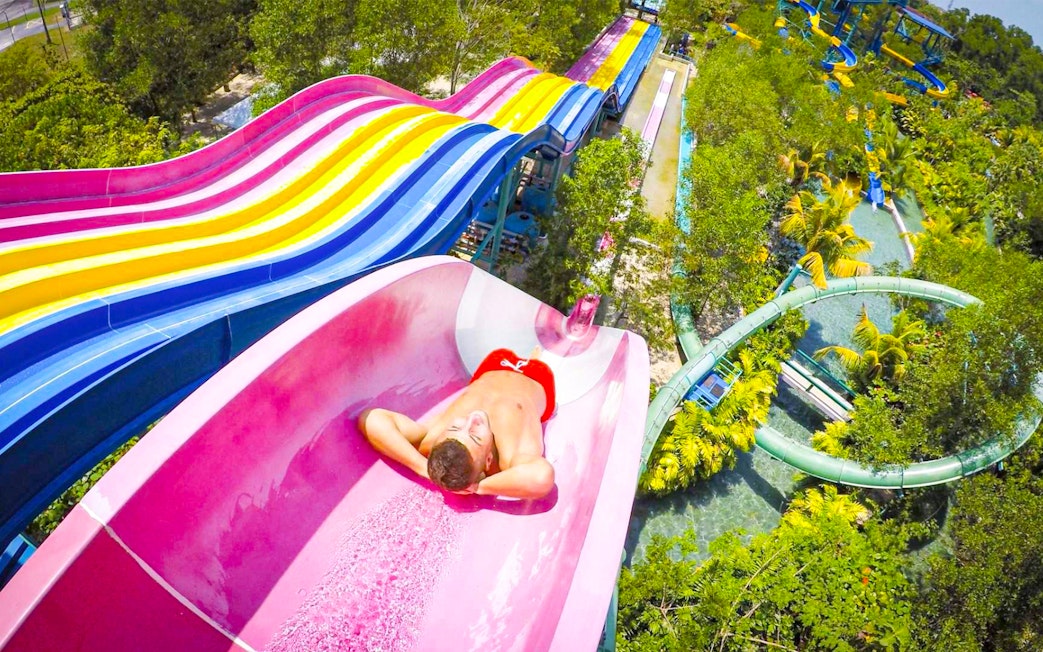 Person sliding down a colorful water slide at ESCAPE Theme Park, Penang.