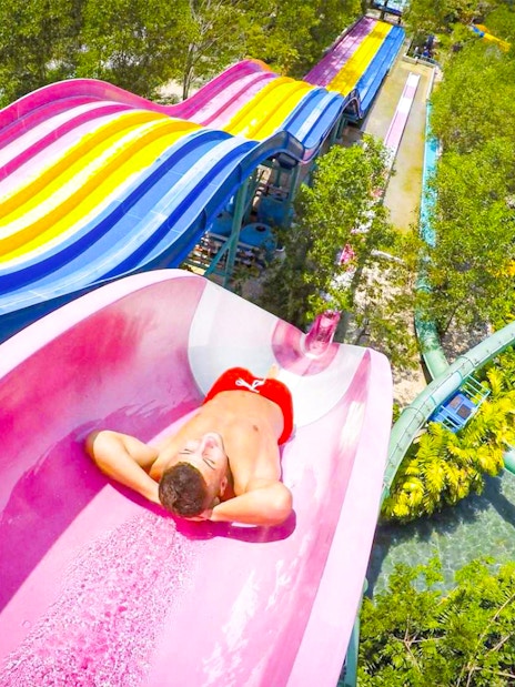 Person sliding down a colorful water slide at ESCAPE Theme Park, Penang.