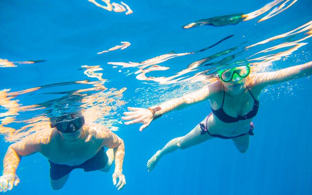 Snorkelers exploring clear waters during Santorini catamaran cruise.