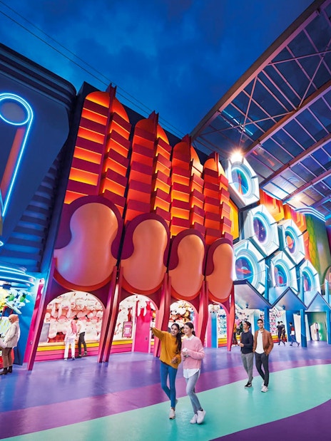 Visitors exploring vibrant neon-lit attractions at Genting SkyWorld Outdoor Theme Park.