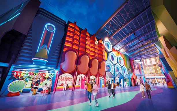 Visitors exploring vibrant neon-lit attractions at Genting SkyWorld Outdoor Theme Park.