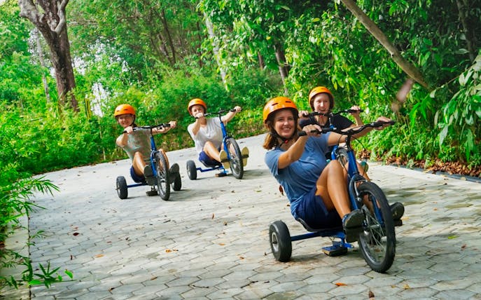 Visitors riding tricycles on a forest path at ESCAPE Petaling Jaya.
