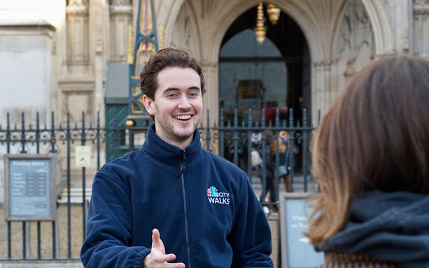 Tour guide greeting visitor outside historic London building.