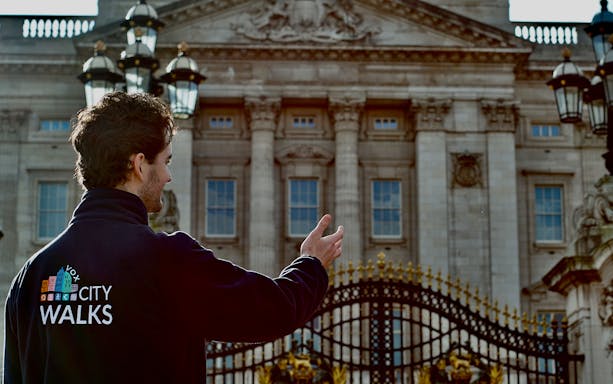Tour guide leading a walking tour outside Buckingham Palace, London.