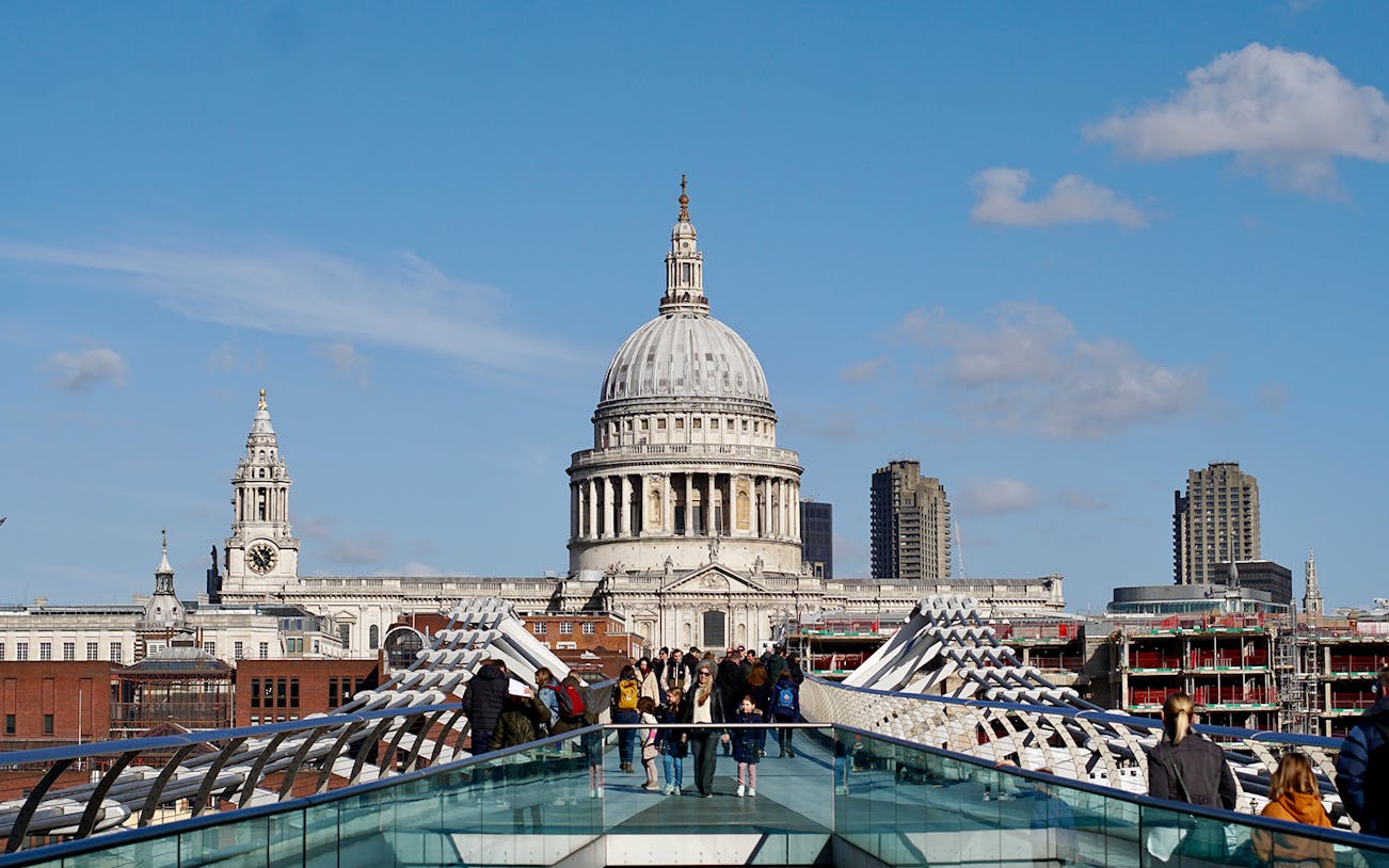 Millennium Bridge leading to St. Paul's Cathedral in London, with people walking.