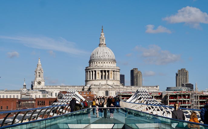 Millennium Bridge leading to St. Paul's Cathedral in London, with people walking.