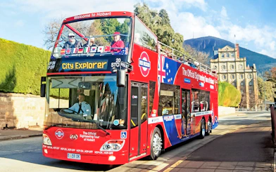 Red double-decker bus on Hobart sightseeing tour with Mount Wellington in the background.