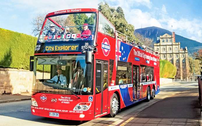 Red double-decker bus on Hobart sightseeing tour with Mount Wellington in the background.