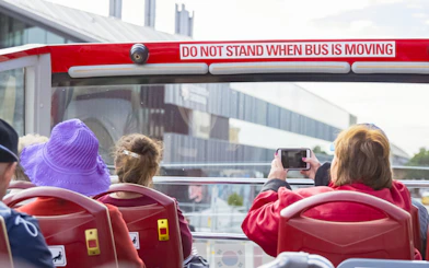 Open-top bus passengers on Hobart sightseeing tour, capturing city views.