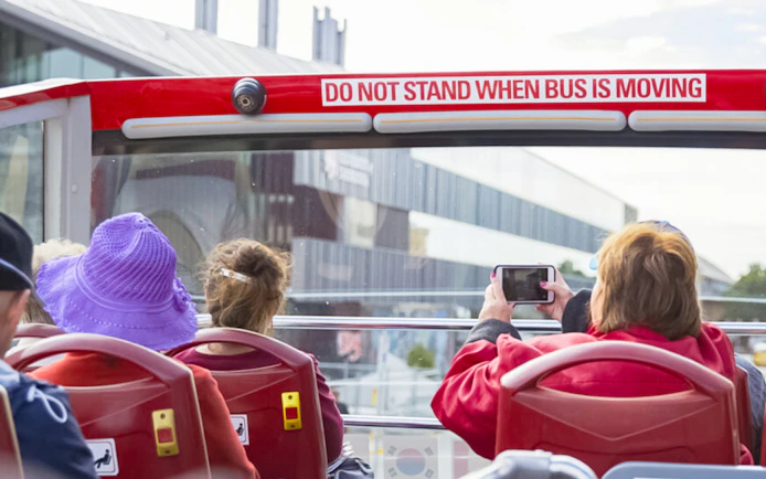 Open-top bus passengers on Hobart sightseeing tour, capturing city views.