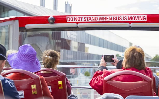 Open-top bus passengers on Hobart sightseeing tour, capturing city views.