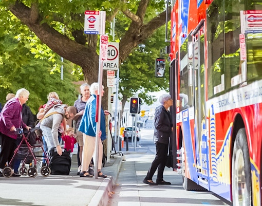 People boarding on hop-on hop-off bus at a city stop.