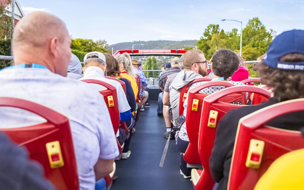Passengers on Hobart hop-on hop-off bus tour with scenic view.