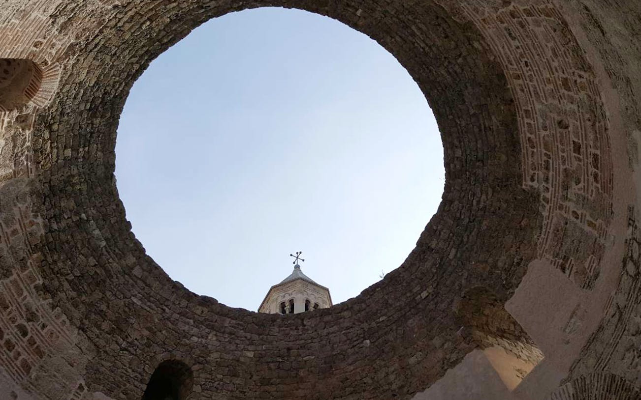 Ancient stone walls of Diocletian's Palace with a view of a bell tower in Split, Croatia.