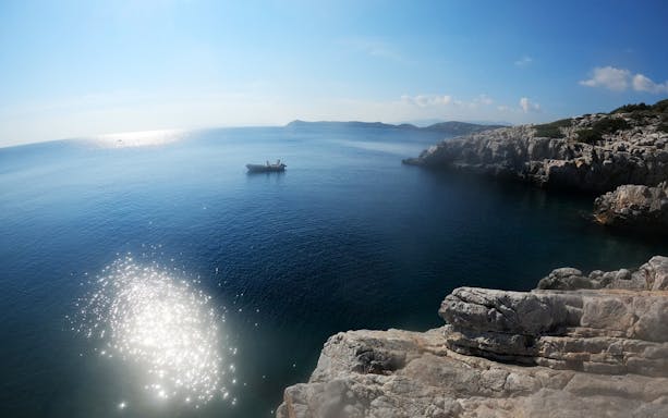 Boat near rocky cliffs in Nea Makri, Athens, ideal for cliff diving trips.