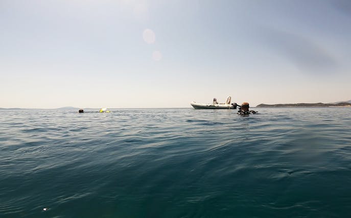 Certified divers exploring waters near Nea Makri, Athens with a boat in the background.