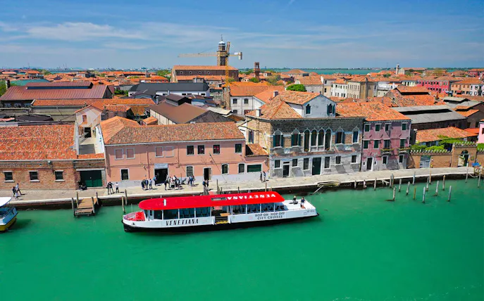 Hop-on hop-off boat at Murano Island, Venice, with colorful buildings and canal.