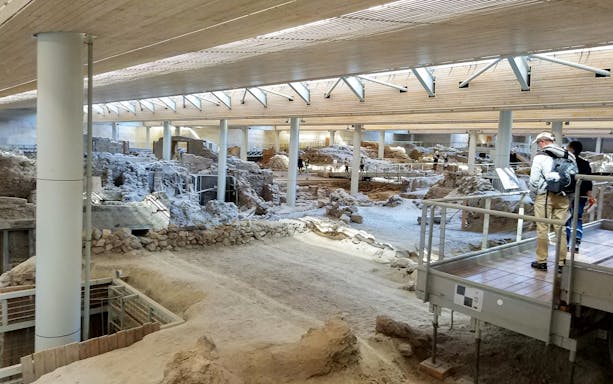 Visitors exploring Akrotiri Prehistoric City ruins on a guided tour in Santorini, Greece.