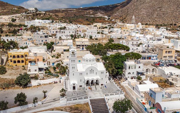 Aerial view of a white church and surrounding village on a Santorini sightseeing bus tour.