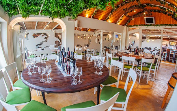 Wine tasting setup in a Santorini restaurant with bottles and glasses on a round table.