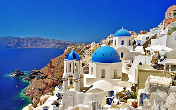 Santorini blue-domed churches overlooking the Aegean Sea on a sightseeing bus tour.