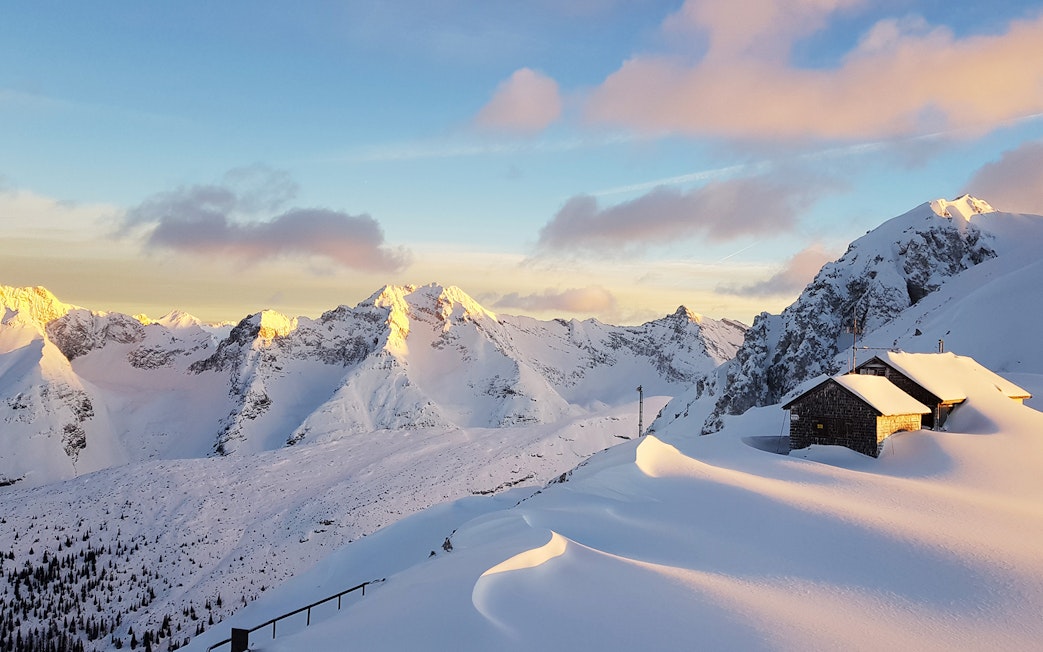 Snow-covered mountains and a cabin at sunset in Innsbruck, Austria.