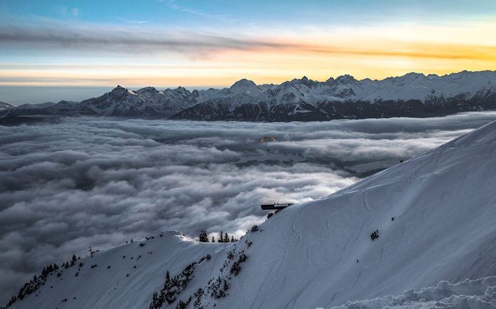 Paraglider over snowy Alps at sunset, Top of Innsbruck PLUS.