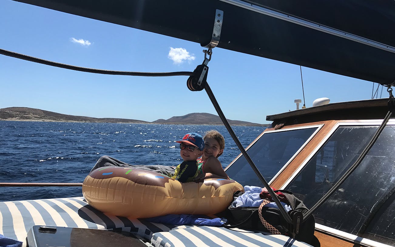 Children relaxing on a boat during a daily cruise to Delos and Rhenia islands.