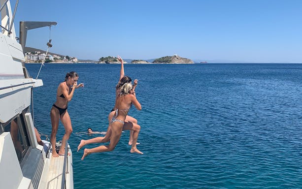 People jumping off a boat into the sea near Delos and Rhenia islands.
