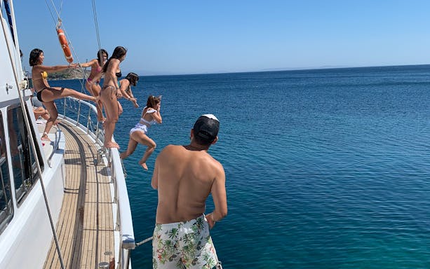 People jumping off a boat into the sea during a Delos and Rhenia islands cruise.