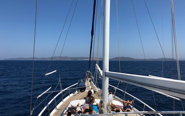 Sailing towards Delos and Rhenia islands on a daily cruise, passengers relaxing on deck.